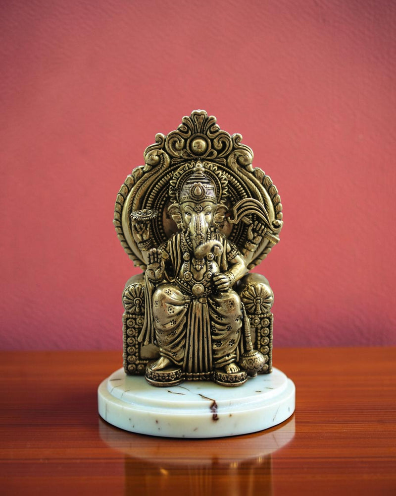 Rigvedaa™ Ornate antique brass Ganesha statue seated on an elaborate throne, detailed traditional Indian artistry.