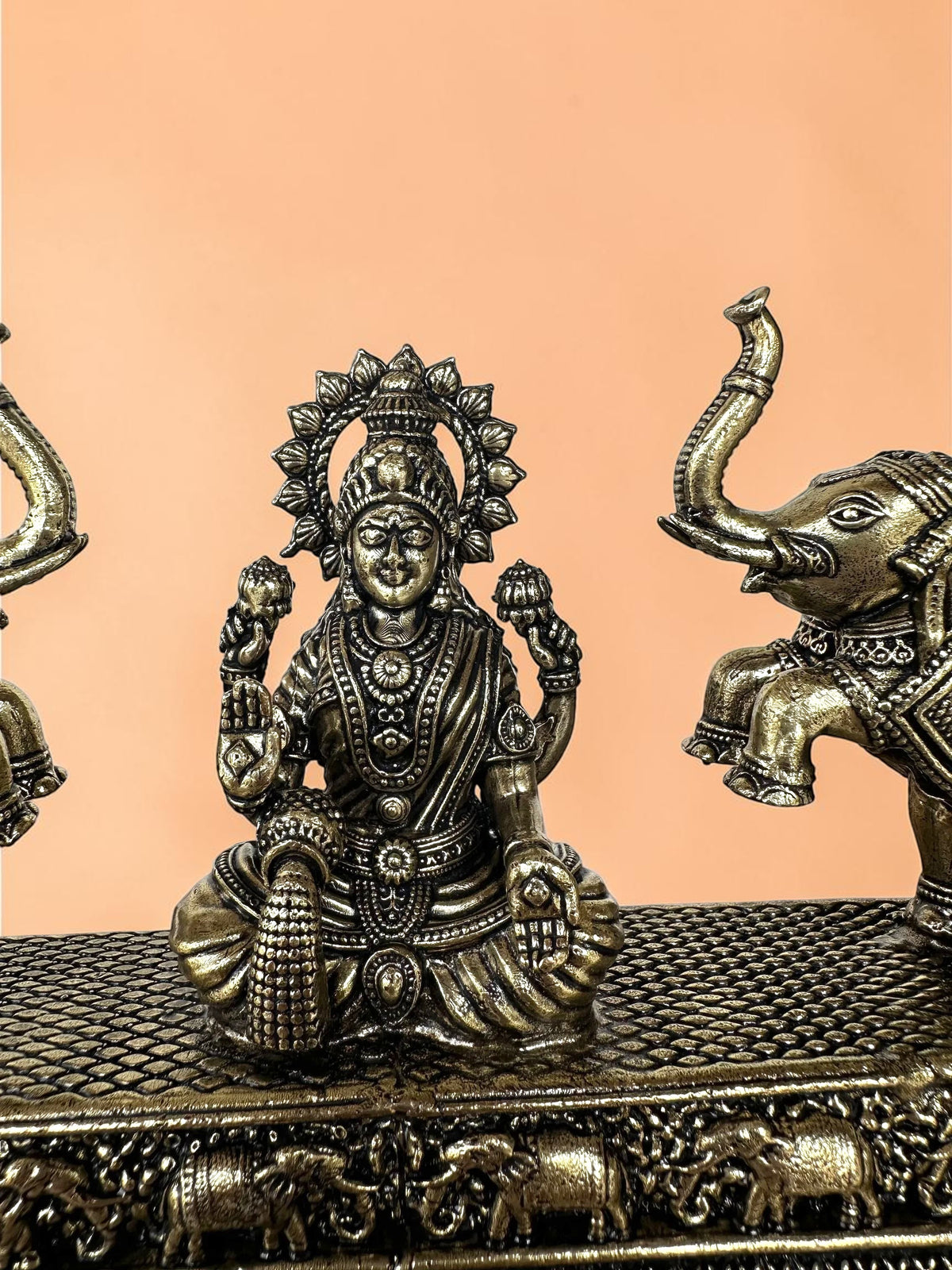 Rigvedaa™ Goddess Lakshmi figurine in antique bronze finish flanked by two elephants on a textured decorative base