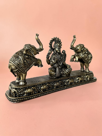Rigvedaa™ antique bronze Goddess Lakshmi figurine flanked by two elephants on a decorative base for home decor.