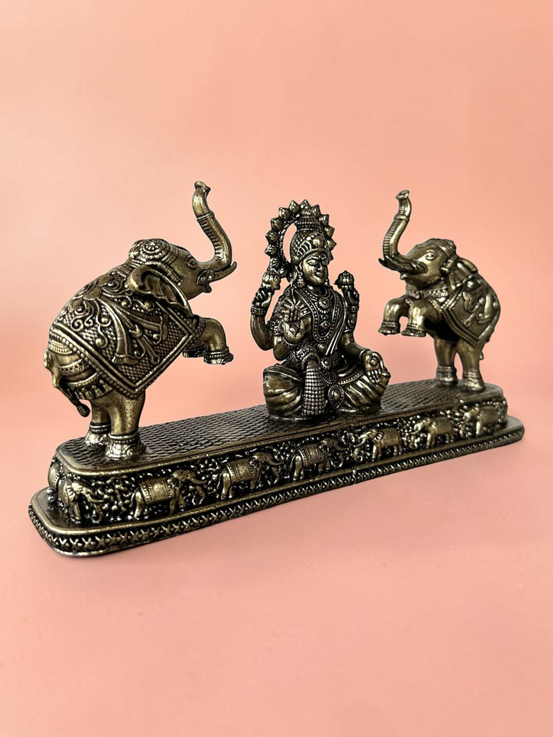 Rigvedaa™ antique bronze Goddess Lakshmi figurine flanked by two elephants on a decorative base for home decor.
