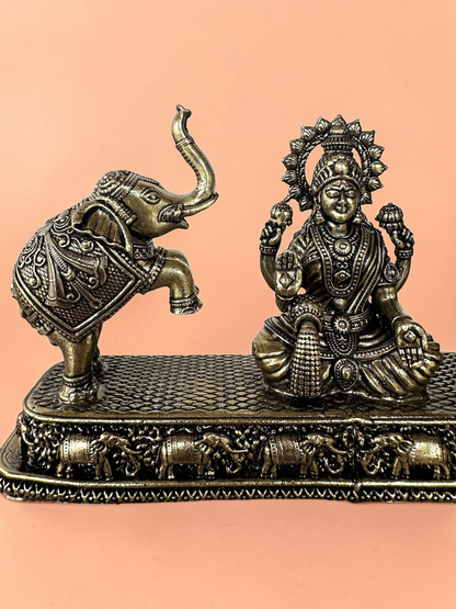 Rigvedaa™ antique bronze Goddess Lakshmi figurine with a ceremonial elephant on a detailed decorative base.