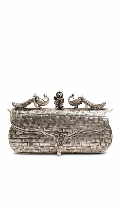 Rigvedaa™ Leela silver plated brass clutch with intricate carvings, peacock details, and a central floral clasp.