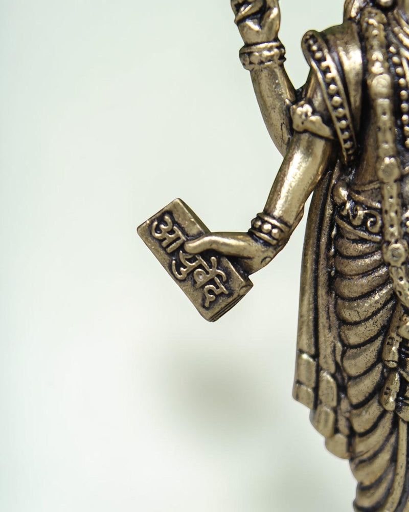 Rigvedaa Lord Dhanvantri brass idol, God of Ayurveda, holding a sacred text. Traditional detailing.