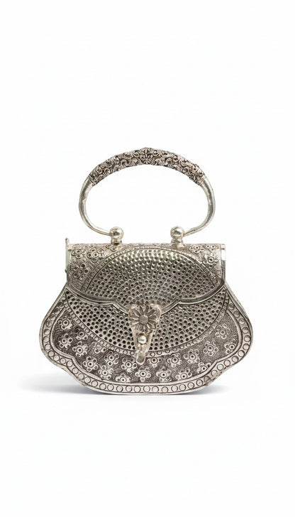 Rigvedaa™ silver plated brass clutch purse with intricate hand-carved floral detailing and a decorative clasp.