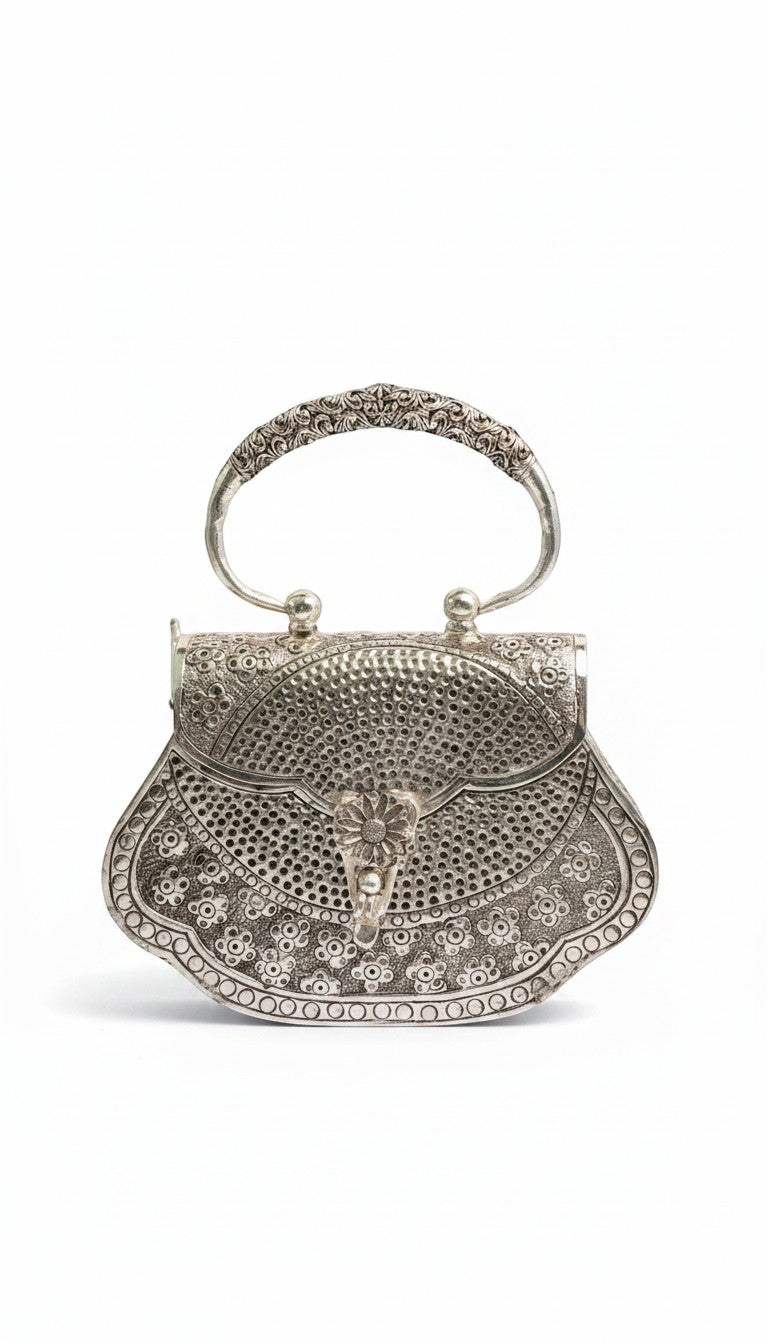 Rigvedaa™ silver plated brass clutch purse with intricate hand-carved floral detailing and a decorative clasp.