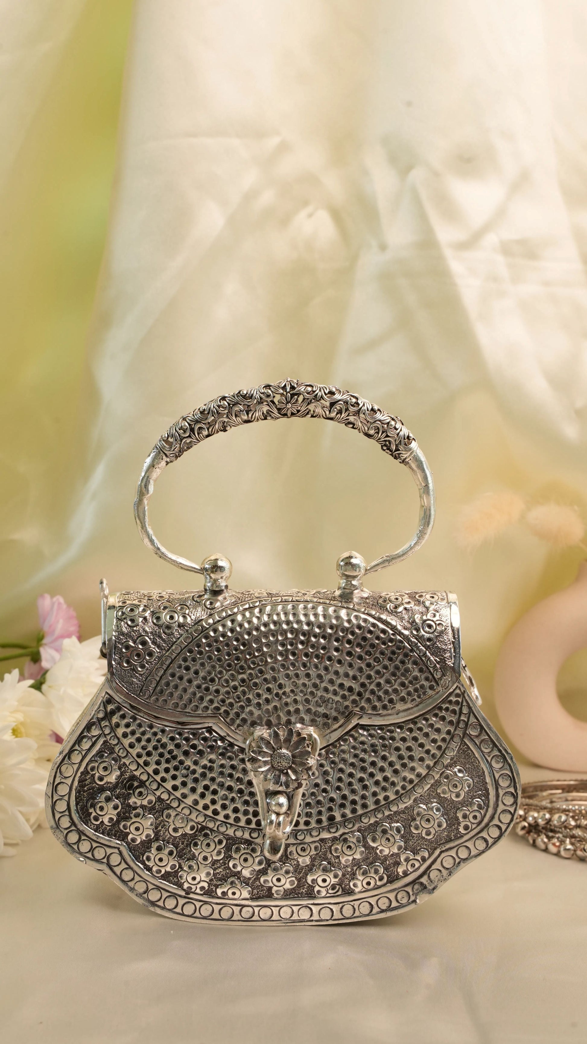 Rigvedaa™ silver plated brass clutch purse with intricate hand-carved floral detailing and a decorative handle. Perfect for festive occasions.