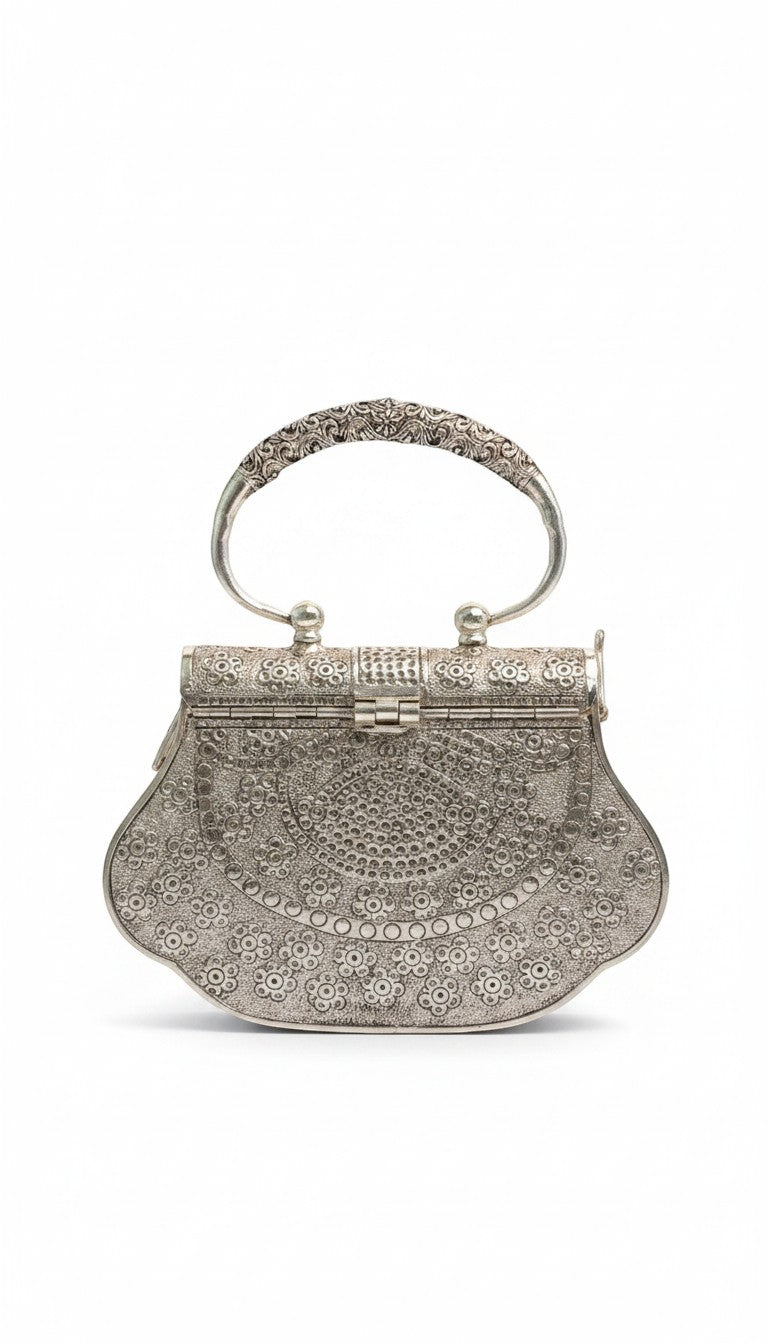 Rigvedaa™ Kanak Silver Clutch: ornate silver-plated brass purse with intricate hand-carved floral detailing and a decorative handle.