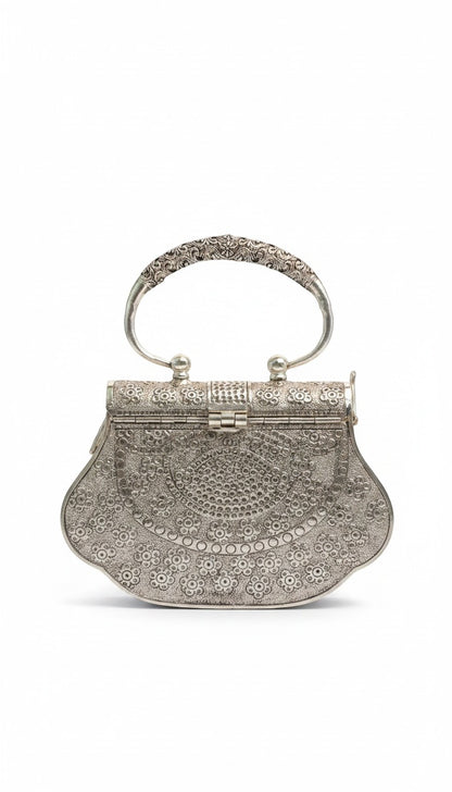 Rigvedaa™ Kanak Silver Clutch: ornate silver-plated brass purse with intricate hand-carved floral detailing and a decorative handle.