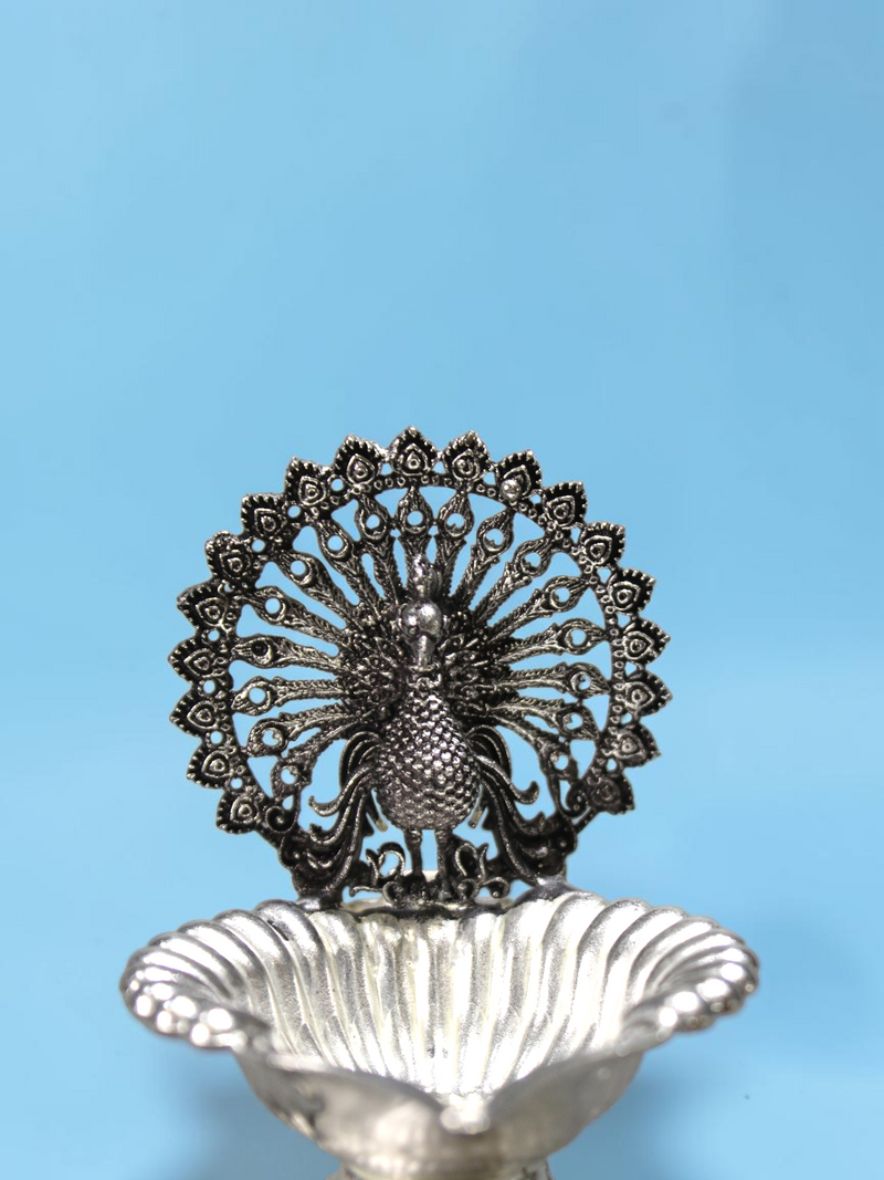 Rigvedaa™ silver-plated brass peacock diya with intricate lotus-shaped bowl for traditional pooja rituals.