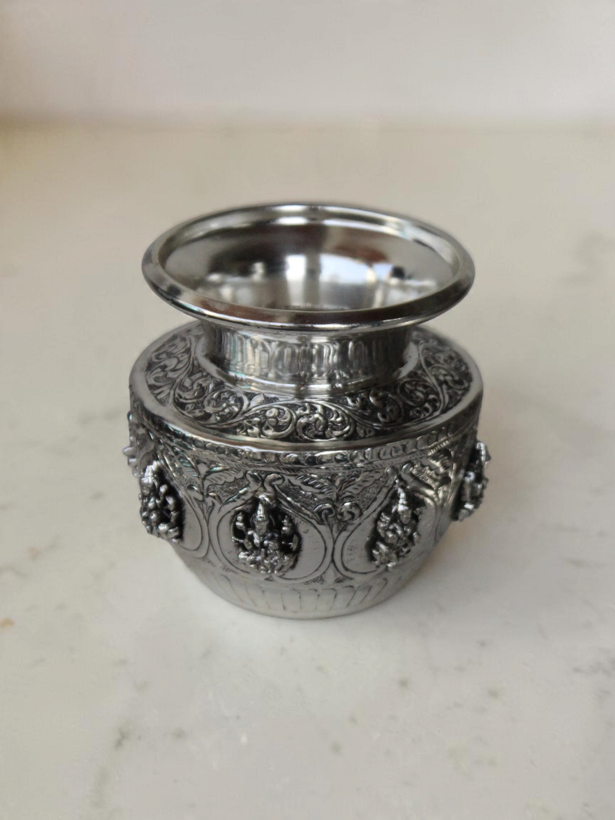Rigvedaa™ 999 silver plated brass Ashta Lakshmi Kalash with intricate embossed floral and deity relief designs.