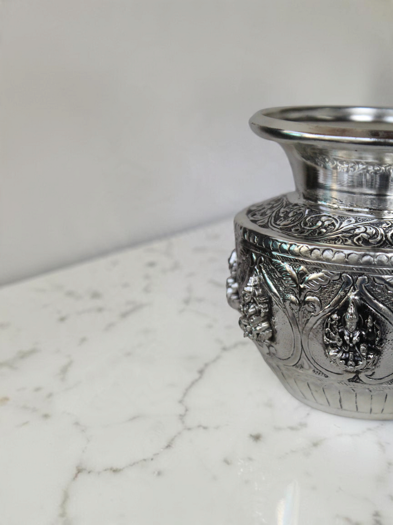 Rigvedaa™ 999 silver plated brass Ashta Lakshmi Kalash with intricate embossed floral and deity relief designs.
