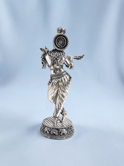 Rear view of an 18-inch Rigvedaa™ silver-plated brass Krishna statue in tribhanga posture playing a flute.