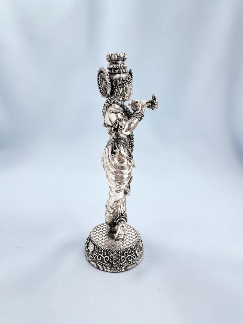 Side view of an 18-inch Rigvedaa™ silver-plated brass Krishna statue in a tribhanga pose playing a flute.