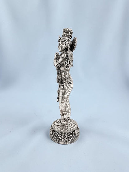 Rigvedaa™ 18-inch silver-plated brass Krishna statue in Tribhanga posture playing the flute on a decorative base.