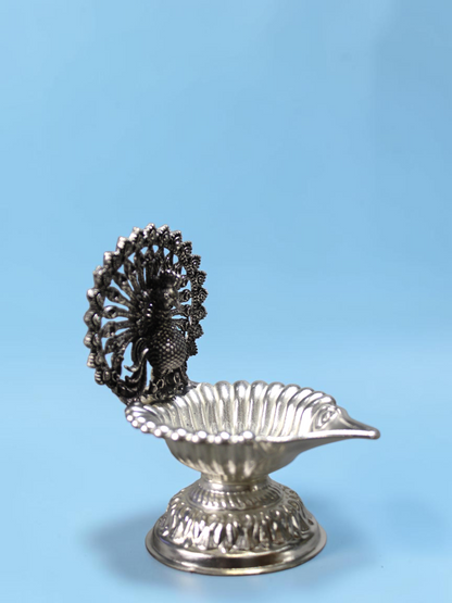 Rigvedaa™ silver plated brass peacock diya featuring an intricate lotus-shaped oil lamp bowl for pooja rituals.