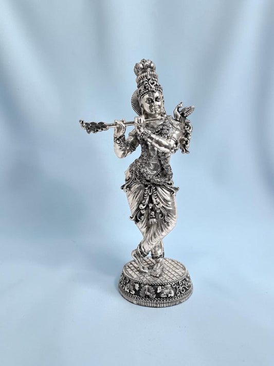 Rigvedaa™ 18-inch silver-plated brass Krishna statue in Tribhanga posture playing a flute with intricate detailing.