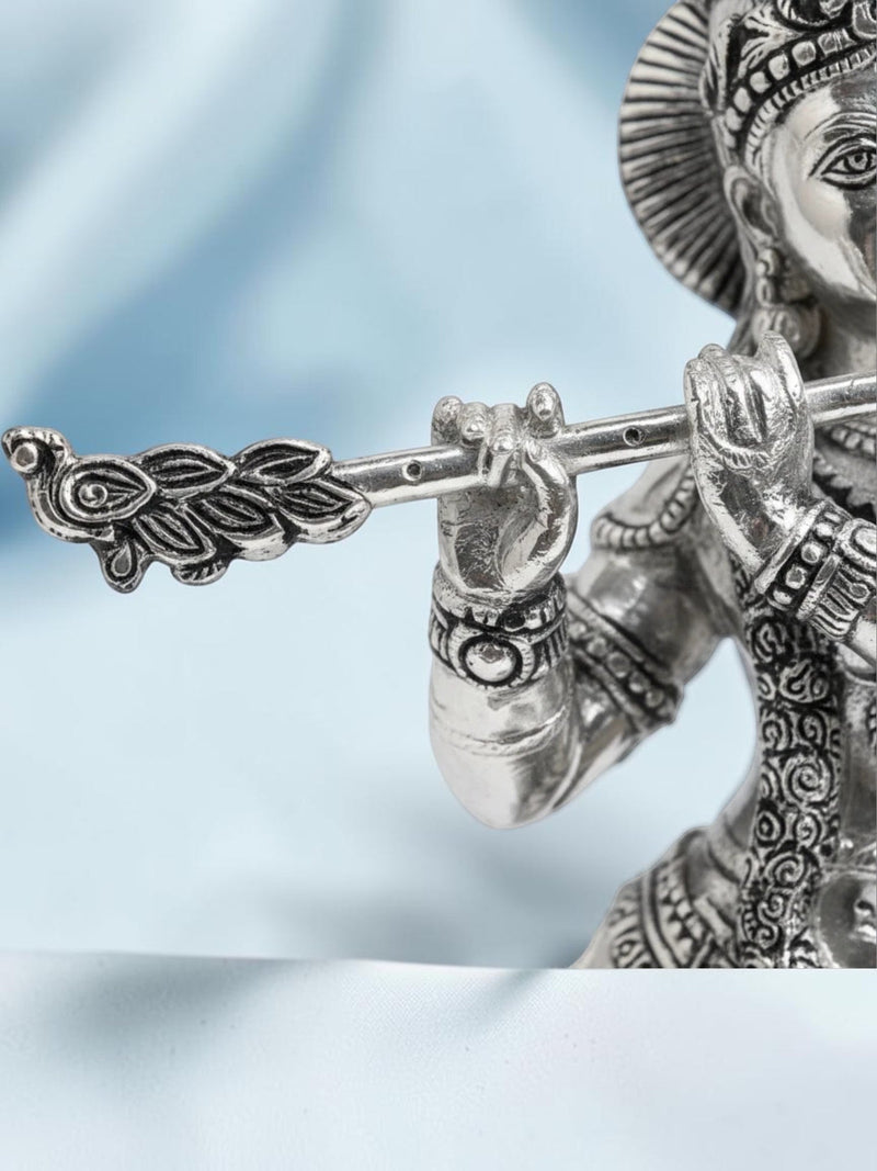 Rigvedaa™ 18-inch silver-plated brass Krishna statue playing a flute, featuring intricate relief work and peacock crown.