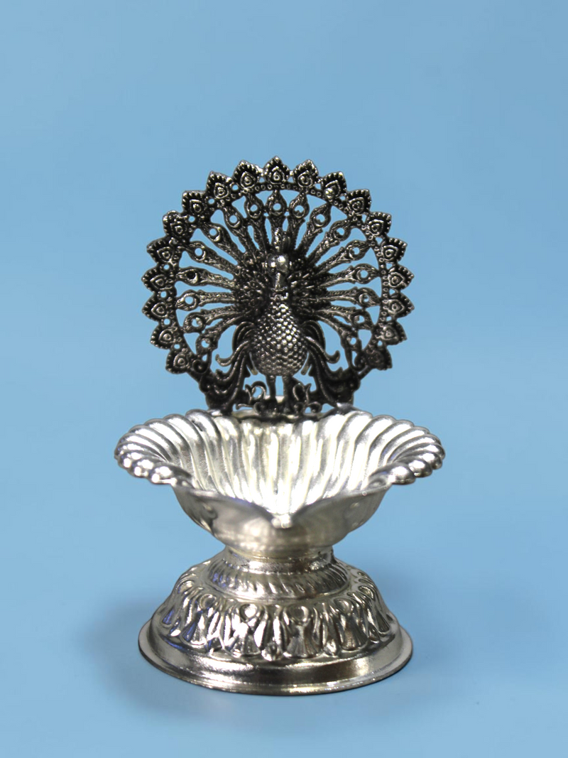 Rigvedaa™ silver plated brass peacock diya oil lamp with intricate lotus bowl design for pooja and home decor.