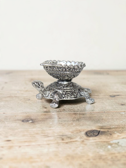 Rigvedaa™ silver-toned turtle diya oil lamp holder with intricate traditional metalwork detailing