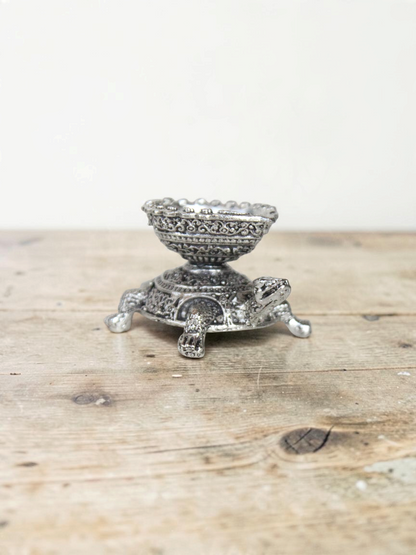 Rigvedaa™ silver-toned turtle diya oil lamp holder with intricate traditional metalwork detailing