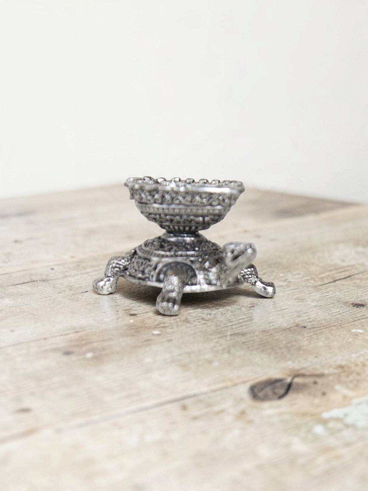 Rigvedaa™ silver-toned turtle diya oil lamp holder with intricate metal detailing for home decor and prayer rituals.