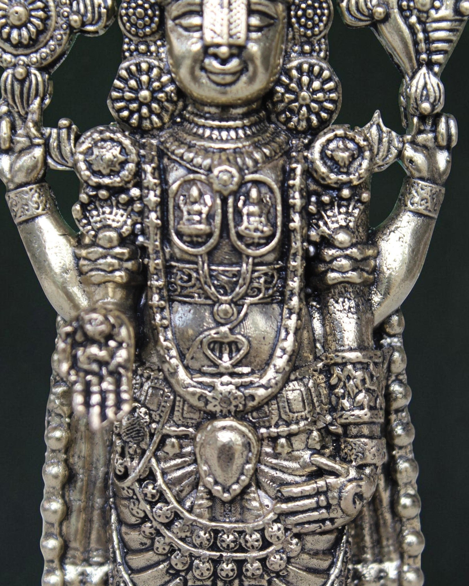 Extreme close-up of Tirupati Balaji brass idol showing divine necklace, chest emblem, Srivatsam and four hands – intricate brass idol detail at Rigvedaa